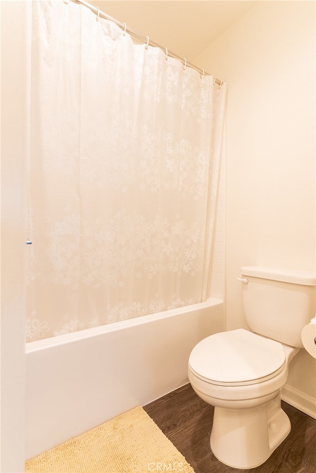 bathroom with shower / bath combo, hardwood / wood-style flooring, and toilet