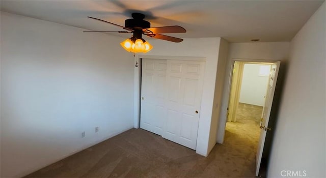 unfurnished bedroom featuring dark colored carpet, ceiling fan, and a closet