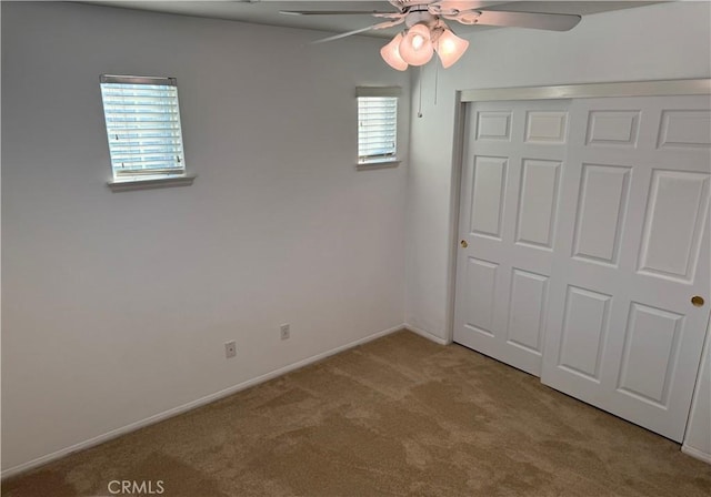 unfurnished bedroom featuring light colored carpet, ceiling fan, and a closet