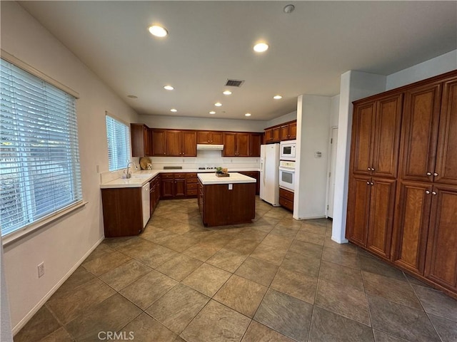 kitchen with a kitchen island, sink, and white appliances