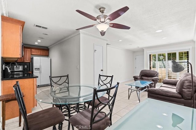 dining room with ceiling fan, crown molding, light tile patterned floors, and sink