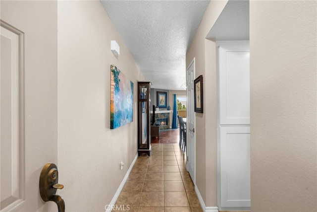 hall featuring a textured ceiling and light tile patterned floors