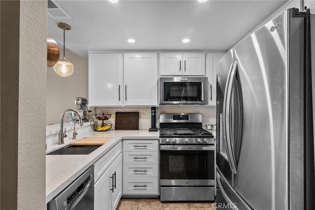 kitchen featuring white cabinets, light tile patterned floors, sink, pendant lighting, and stainless steel appliances