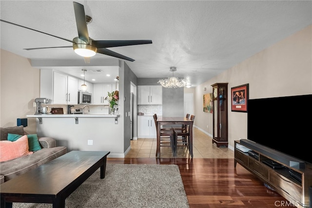 living room featuring hardwood / wood-style flooring, a textured ceiling, and ceiling fan with notable chandelier