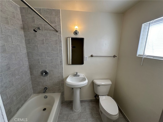 bathroom featuring tiled shower / bath, toilet, and tile patterned flooring