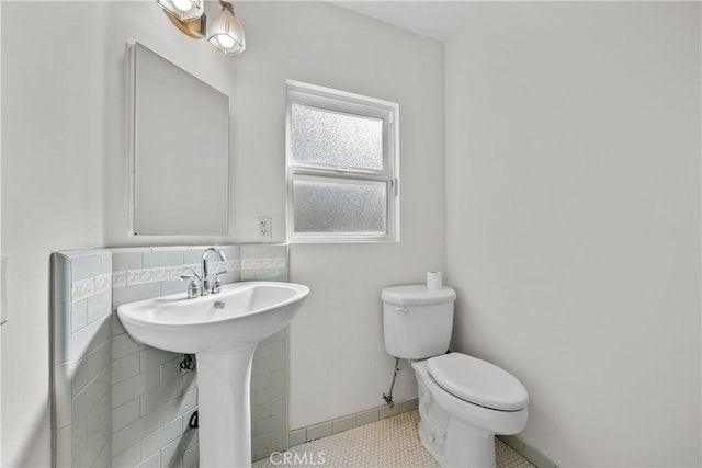 bathroom featuring toilet, tile patterned floors, tile walls, and sink