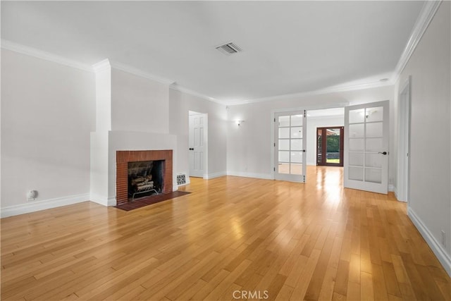 unfurnished living room featuring ornamental molding, light hardwood / wood-style floors, and a brick fireplace