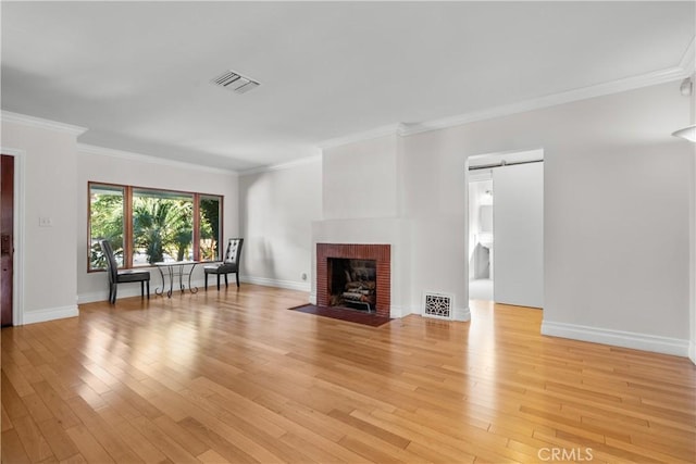 unfurnished living room with a brick fireplace, crown molding, and light wood-type flooring