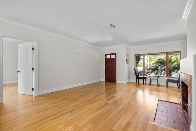 entryway with light wood-type flooring, a brick fireplace, and ornamental molding