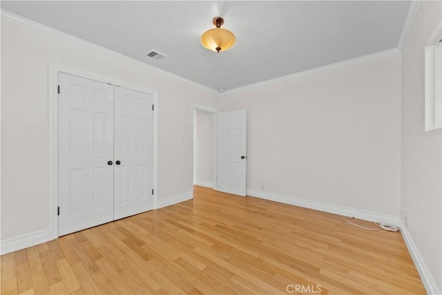 unfurnished bedroom featuring a closet, ornamental molding, and light wood-type flooring