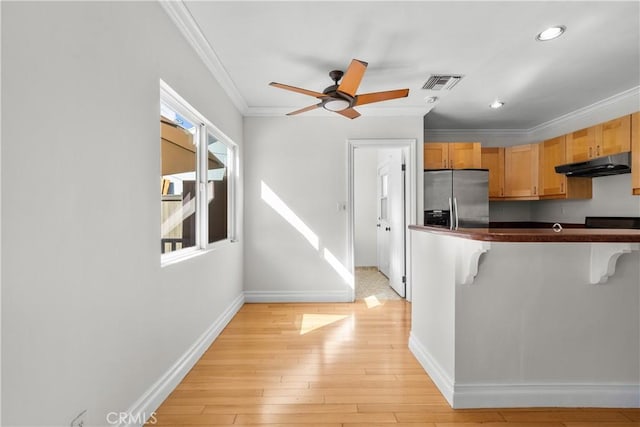 kitchen featuring a kitchen bar, stainless steel refrigerator with ice dispenser, light wood-type flooring, ceiling fan, and crown molding