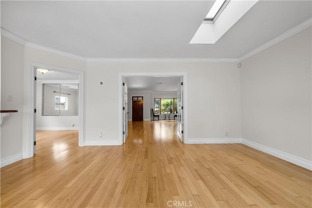 spare room featuring ornamental molding, a skylight, and light hardwood / wood-style floors