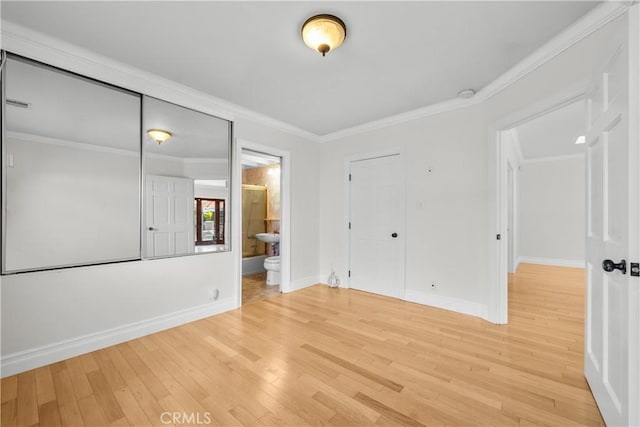 unfurnished bedroom featuring hardwood / wood-style flooring, ensuite bathroom, crown molding, and a closet