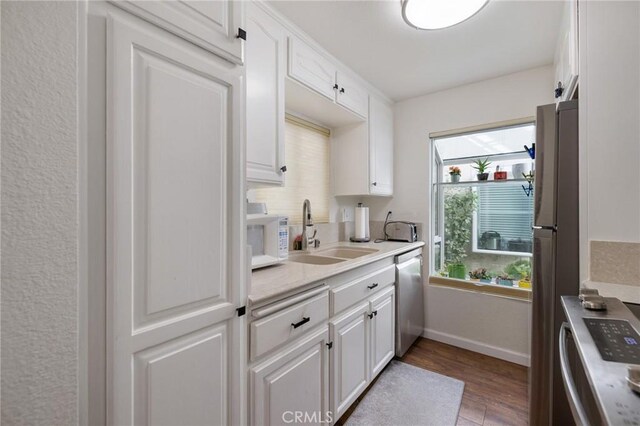 kitchen with hardwood / wood-style floors, white cabinetry, sink, and stainless steel appliances