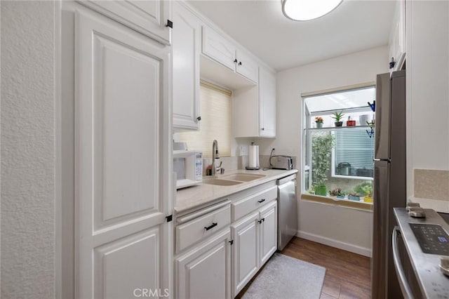 18411 Hatteras St Unit 120, Tarzana, CA 91356 - kitchen featuring a sink, appliances with stainless steel finishes, light wood finished floors, white cabinets, and baseboards