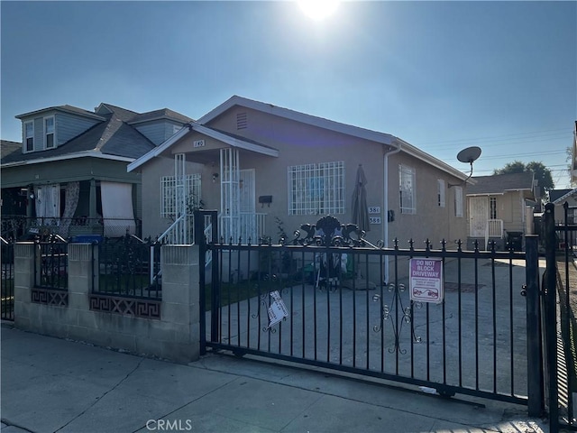 138 E 60th St, Los Angeles, CA 90003 - view of front facade with a fenced front yard, stucco siding, and a gate
