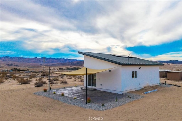69444 Valle Vista Rd Unit 29, Palms, CA 92277 - back of property with a mountain view, a patio area, metal roof, and solar panels