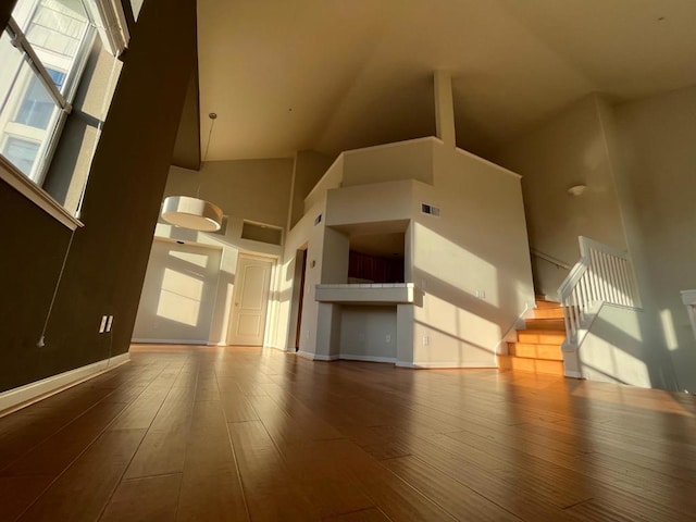 unfurnished living room featuring wood-type flooring and a high ceiling