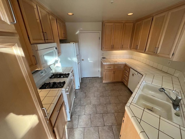 kitchen featuring tile counters, sink, light brown cabinets, and white appliances