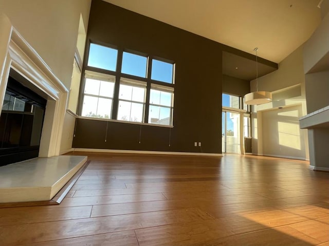 unfurnished living room with a towering ceiling and hardwood / wood-style floors