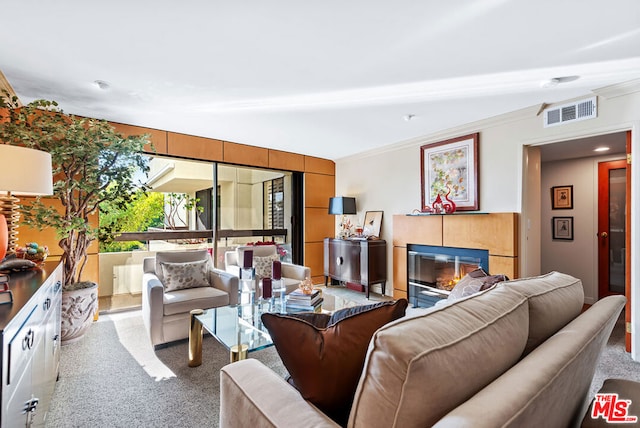 carpeted living room featuring a tiled fireplace and ornamental molding