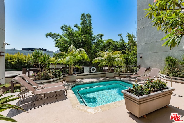 view of pool with a hot tub and a patio