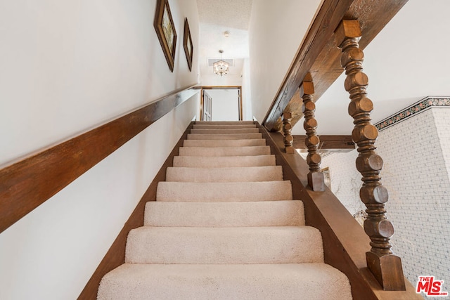 stairway featuring a notable chandelier