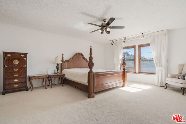 bedroom featuring a textured ceiling, light colored carpet, and ceiling fan