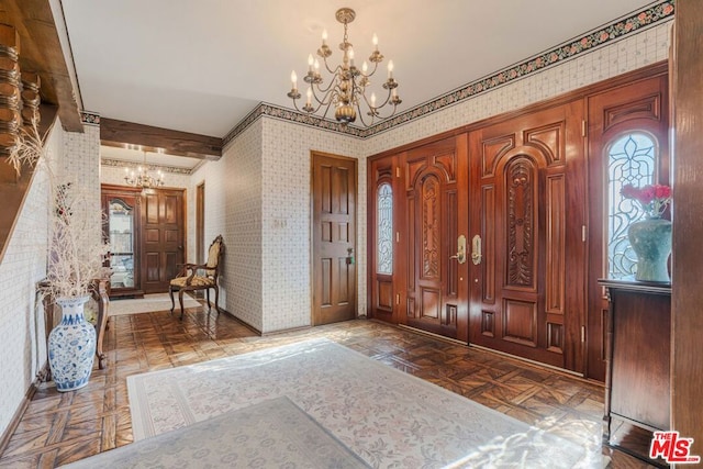 entrance foyer featuring a chandelier, beam ceiling, and parquet floors