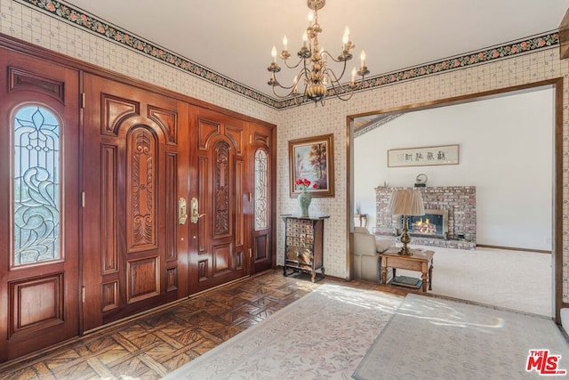 foyer featuring a fireplace, dark parquet floors, and a chandelier