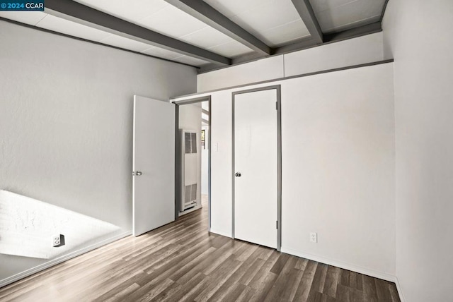 unfurnished bedroom with beamed ceiling and wood-type flooring