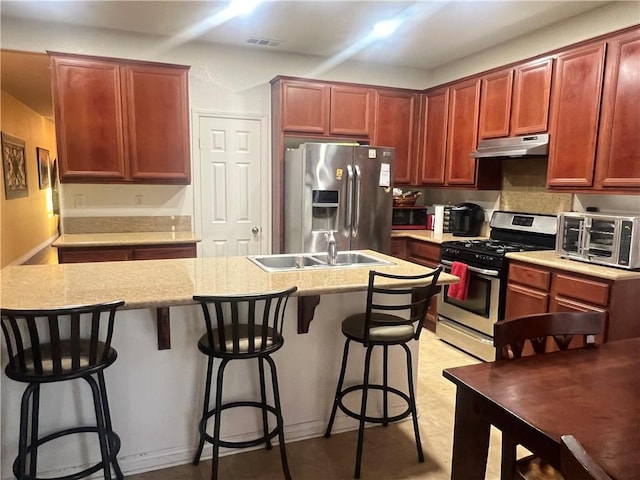 kitchen with a breakfast bar, appliances with stainless steel finishes, a center island with sink, and sink