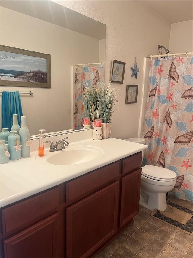 bathroom featuring curtained shower, tile patterned flooring, vanity, and toilet