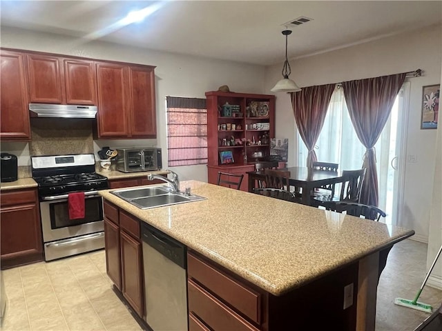 kitchen with an island with sink, stainless steel appliances, hanging light fixtures, and sink