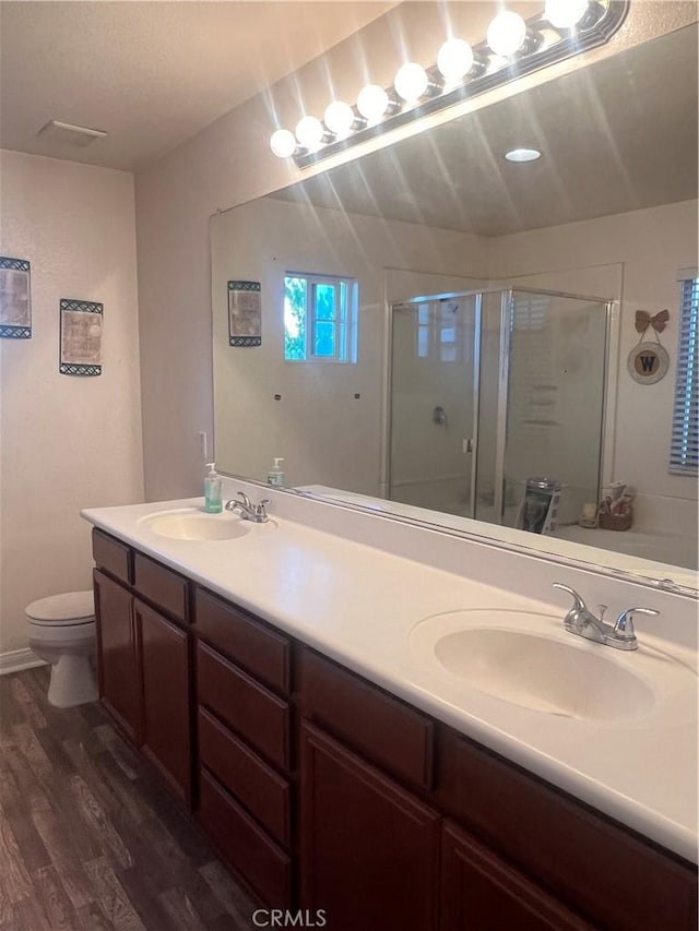 bathroom with wood-type flooring, vanity, toilet, and a shower with door