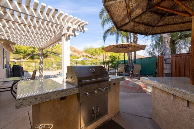 view of patio featuring exterior kitchen, grilling area, and a pergola