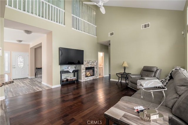 living room with ceiling fan, hardwood / wood-style flooring, high vaulted ceiling, and a fireplace