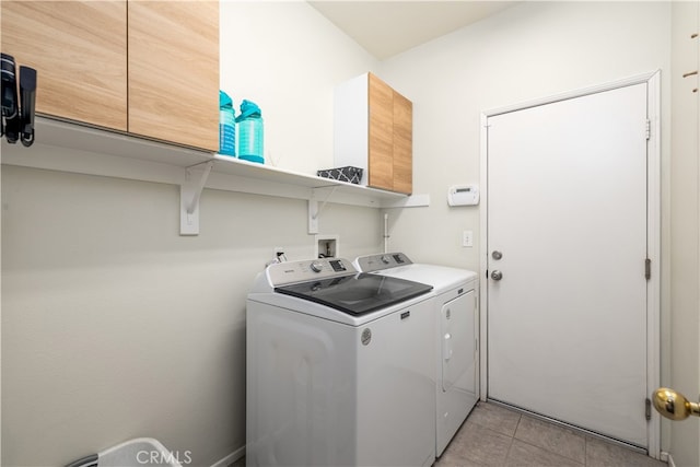 washroom featuring light tile patterned flooring, washing machine and dryer, and cabinets