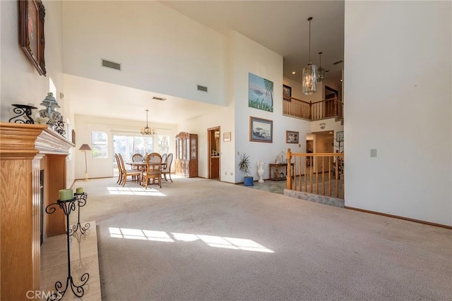 unfurnished living room featuring light carpet, a high ceiling, and an inviting chandelier