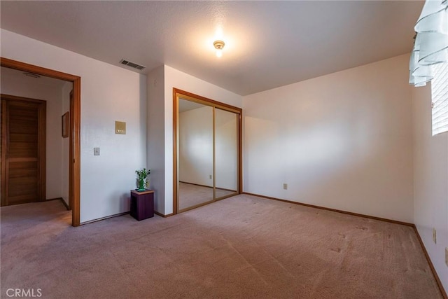 unfurnished bedroom with light colored carpet and a closet