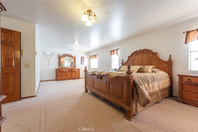 bedroom with light carpet, a chandelier, and multiple windows