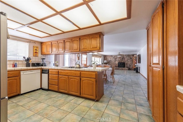 kitchen featuring kitchen peninsula, black electric stovetop, dishwasher, and tile countertops