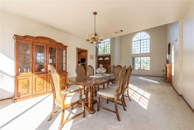 dining room featuring a high ceiling, light colored carpet, and an inviting chandelier