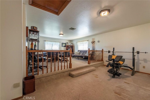 workout area with light carpet and a textured ceiling