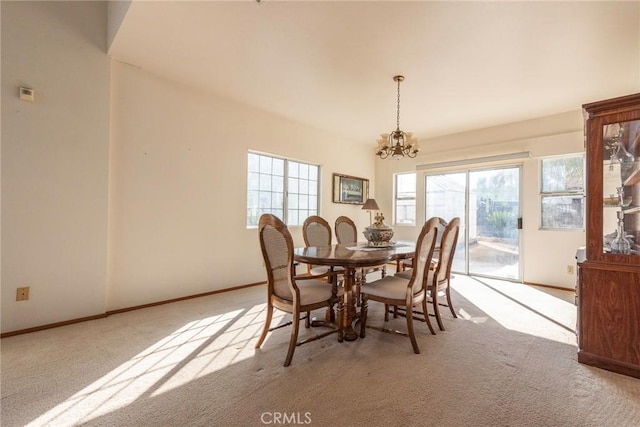 carpeted dining area with a chandelier