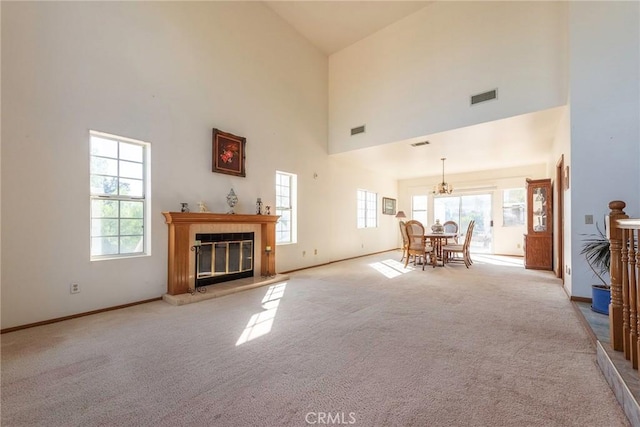 unfurnished living room with a towering ceiling, light colored carpet, and a healthy amount of sunlight