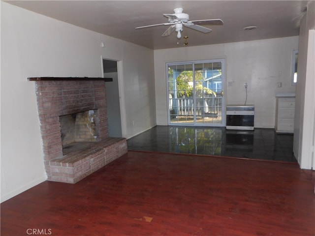 unfurnished living room featuring ceiling fan, dark wood-type flooring, and a brick fireplace