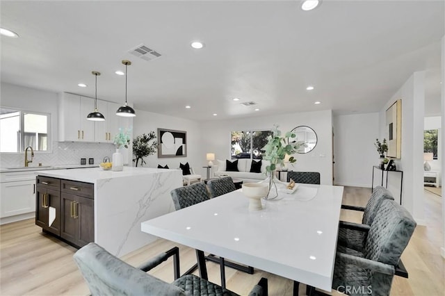 dining room with light wood-type flooring, a wealth of natural light, and sink