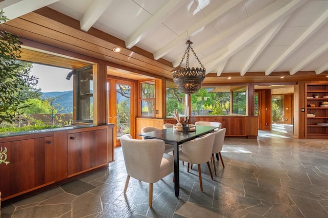 dining area with a mountain view, beam ceiling, a notable chandelier, and wooden walls