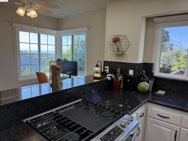 kitchen with white cabinets, high end stainless steel range oven, a wealth of natural light, and dark stone counters